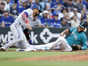Eugenio Suarez #28 of the Seattle Mariners reacts after Lourdes Gurriel Jr. #13 of the Toronto Blue Jays slid into him at third base during the fourth inning at T-Mobile Park on July 08, 2022 in Seattle, Washington.