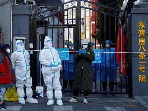Security personnel in protective suits stand at the gate of a residential compound that is under lockdown as outbreaks of COVID-19 continue in Beijing, Oct. 22, 2022.