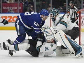 Oct 22, 2021; Toronto, Ontario, CAN; Toronto Maple Leafs forward Michael Bunting (58) knocks San Jose Sharks defenseman Jacob Middleton (21) to the ice in front of San Jose Sharks goaltender Adin Hill (33) during the second period at Scotiabank Arena.