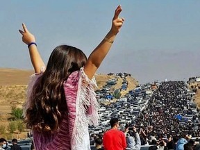 This image posted to Twitter reportedly on Wednesday, Oct. 26, 2022, shows an unveiled woman standing on top of a vehicle as thousands make their way towards Aichi cemetery in Saqez, Mahsa Amini's home town in the western Iranian province of Kurdistan, to mark 40 days since her death.