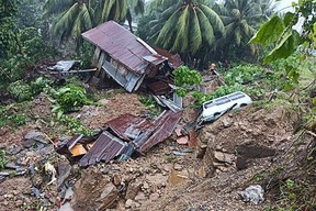 This handout photo taken and received Friday, Oct. 28, 2022 from the Philippines Marines Battalion Landing Team 5 shows a resident standing next to a damaged house and vehicle after a landslide due to heavy rains brought by Tropical Storm Nalgae in Parang, Maguindanao province.