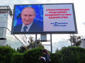 A pedestrians walks past a billboard signed by the pro-Russian right-wing group 'Nasi' (Ours) showing Russian President Vladimir Putin and a sentence reading, "Happy birthday to President Vladimir Putin from the Serbian brothers!" in Belgrade on Oct. 7, 2022.
