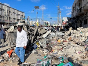 A man walks past wreckages of destroyed vehicles near the ruins of a building at the scene of an explosion along K5 street in Mogadishu, Somalia Oct. 30, 2022.