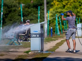 Thomas George, an employee with The Cleaning Company, hoses down a garbage and recycling bin along Broadview Ave. in Toronto, Ont. on Wednesday, Oct. 5, 2022.