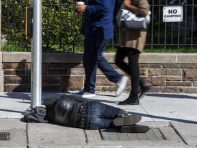 A person sleeps on the street on Simcoe St., at King St. W. in downtown Toronto, Ont. on Wednesday, Oct. 5, 2022.