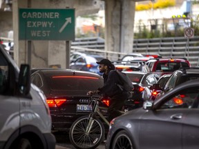 A cyclist makes their way through the cars lined up for the ramp to the Gardiner Expressway at Lower Jarvis St. and Lake Shore Blvd. E. during the afternoon rush hour in Toronto, Ont. on Thursday, Oct. 6, 2022.