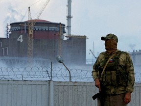 Ein Soldat mit einer russischen Flagge auf seiner Uniform steht Wache in der Nähe des Kernkraftwerks Saporischschja außerhalb der von Russland kontrollierten Stadt Enerhodar, Ukraine, 4. August 2022.