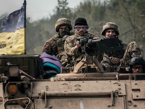 Ukrainian soldiers ride on an armoured vehicle near the recently retaken town of Lyman in Donetsk region on October 6, 2022.
