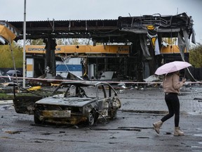 A woman passes by a gas station destroyed by Tuesday's Russian military strike, as Russia's attack on Ukraine continues, in Dnipro, Ukraine, Wednesday, Oct. 26, 2022.