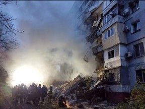 Rescuers gather past a residential building damaged after a strike in Zaporizhzhia, amid the Russian invasion of Ukraine on Oct. 9, 2022.