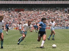 (FILES) In this file photo taken on June 22, 1986 Argentinian forward Diego Armando Maradona runs past English defenders Terry Butcher (L) and Terry Fenwick (2nd L) on his way to scoring his second goal during the World Cup quarterfinal soccer match between Argentina and England. FILE / Getty Images
