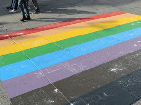 People walk past a Pride flag crosswalk in Calgary on Sunday, Aug. 18, 2019.
