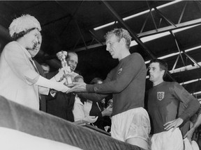 FILE: Queen Elizabeth of England presents the Jules Rimet Cup to Bobby Moore, captain of England’s national soccer team, as her husband Prince Philip (C) and forward Geoff Hurst (R) look on after England beat West Germany 4-2 in extra time in the World Cup final 30 July 1966 at Wembley stadium in London.