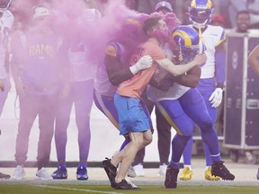 A protester is hit by Los Angeles Rams defensive end Takkarist McKinley, middle left, and linebacker Bobby Wagner during the first half of an NFL football game between the San Francisco 49ers and the Rams in Santa Clara, Calif., Monday, Oct. 3, 2022.
