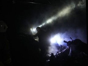 Ukrainian firefighters work among debris following a Russian shelling in Kharkiv, Ukraine, early Saturday, Oct. 8, 2022.