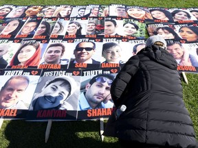A woman places a placard with the photo of a person killed on Flight 752 during a protest on Parliament Hill, Tuesday, Oct. 4, 2022 in Ottawa.