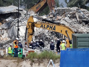Rescue workers watch as excavators are used to dig through the rubble of the collapsed 12-story Champlain Towers South condo building on July 9, 2021 in Surfside, Florida.
