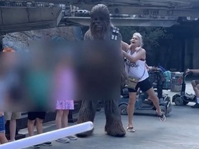 A woman approaches Chewbacca and Rey, another Star Wars character and pushes Chewbacca.