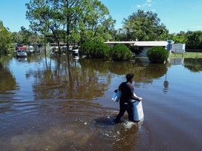 A man walks through a flooded street with his belongings from his house in the Orlovista neighborhood following Hurricane Ian on October 1, 2022 in Orlando, Florida.