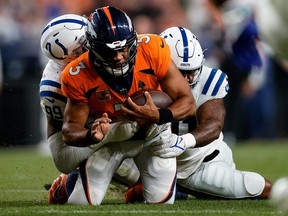 Oct 6, 2022; Denver, Colorado, USA; Denver Broncos quarterback Russell Wilson (3) is tackled by Indianapolis Colts defensive tackle DeForest Buckner (99) and defensive end Yannick Ngakoue (91) in the third quarter at Empower Field at Mile High.
