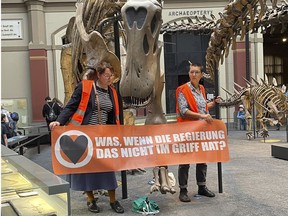 Two climate activists carrying a banner "What if the government can't handle it?" have stuck themselves to the handrails of a dinosaur at Berlin's Museum of Natural History in Berlin, Germany, Sunday, Oct. 30, 2022.