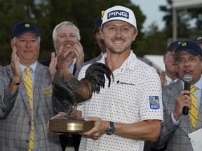 Mackenzie Hughes of Canada hoists the Sanderson Farms Championship golf tournament trophy in Jackson, Miss., Sunday, Oct. 2, 2022. Hughes won on the second hole of a sudden death playoff.