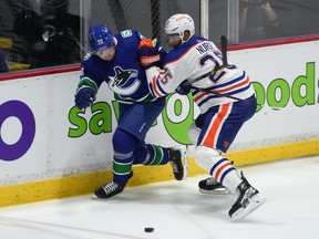 Edmonton Oilers' Darnell Nurse (25) checks Vancouver Canucks' Curtis Lazar (20) during the first period of a pre-season NHL hockey game in Abbotsford, B.C., on Wednesday, October 5, 2022.