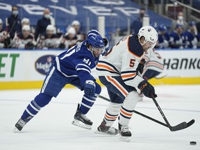 Jan 5, 2022; Toronto, Ontario, CAN; Edmonton Oilers defenseman Cody Ceci (5) tries to control the puck as Toronto Maple Leafs forward John Tavares (91) closes in during the first period at Scotiabank Arena.