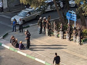 A UGC picture posted on Twitter on October 27, 2022, reportedly shows Iranian women sitting without a veil across from security forces in a square in Tehran.