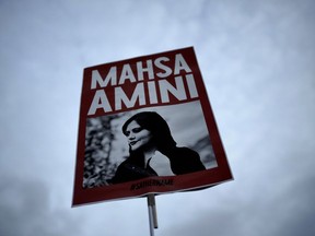 A woman holds a placard with a picture of Iranian Mahsa Amini