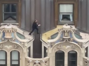 Man jumping across rooftop awnings of NYC high-rise.