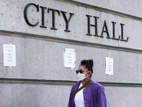 A person walks past signs posted outside City Hall calling for the resignations of L.A. City Council members Kevin de Leon and Gil Cedillo in the wake of a leaked audio recording on October 18, 2022 in Los Angeles.