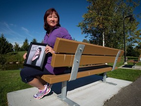 Carol Todd holds a photograph of her late daughter Amanda Todd while sitting on a bench dedicated to her at Settlers Park in Port Coquitlam, B.C., on Sunday October 5, 2013. Todd says police need to take online harassment seriously and not shame victims into thinking they brought their torment on themselves.THE CANADIAN PRESS/Darryl Dyck