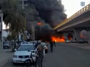 Flames from a huge fire are seen after a fuel tanker truck crashed into an overpass by a rail line in Aguascalientes, Mexico Thursday.