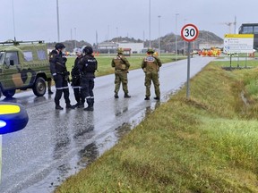 Police and personnel from the Home Guard stand guard outside the land plant of the Ormen Lange gas field after a person called in a bomb threat against the plant, in Aukra, Norway, Thursday Oct. 13, 2022.