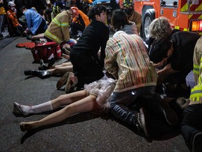 This picture taken on Oct. 29, 2022 shows emergency workers and others assisting people who were caught in a Halloween stampede in the district of Itaewon in Seoul.