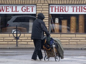 A person crosses a road in Ottawa by an inspirational sign on a business, April 3, 2020.