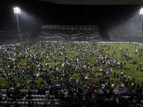 Fans of Gimnasia y Esgrima La Plata affected by tear gas invade the field after the match between Gimnasia y Esgrima La Plata and Boca Juniors in the Liga Profesional 2022 was suspended due clashes between supporters and the police outside the stadium, at Juan Carmelo Zerillo Stadium, in La Plata, Argentina October 6, 2022.