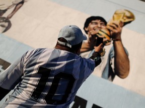 A fan of Argentine soccer superstar Diego Armado Maradona takes a picture of a mural as he celebrates the idol's 35th anniversary of the "goal of the century", against England during the 1986 World Cup played in Mexico, in Buenos Aires, Argentina June 22, 2021.