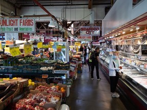 People shop for produce and seafood at the Granville Island Market in Vancouver, on Wednesday, July 20, 2022.