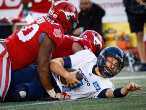 Toronto Argonauts quarterback McLeod Bethel-Thompson is sacked by Isaac Adeyemi-Berglund and Shawn Lemon of the Calgary Stampeders during CFL football in Calgary on Saturday night.