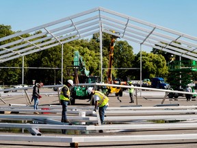 Workers erect a hangar-sized tent, Sept. 27, 2022, in the parking lot of Orchard Beach, in the Bronx borough of New York City, as temporary shelter for thousands of international migrants who have been bused into the Big Apple.