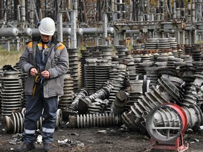 A worker examines destruction as he repairs power lines destroyed after a missile strike on a power plant, in an undisclosed location of Ukraine, on October 27, 2022.