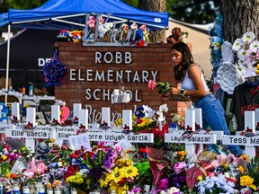 In this file photo taken on May 28, 2022 a girl lays flowers at a makeshift memorial at Robb Elementary School in Uvalde, Texas.
