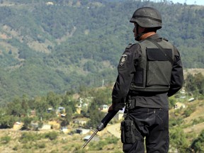 A Oaxaca State Police officer stands watch the entrance to the San Juan Copala community in Oaxaca, Mexico, on April 28, 2010.