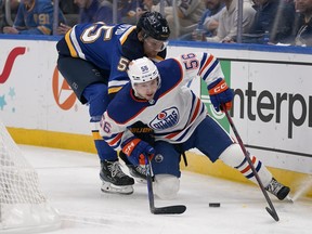 Edmonton Oilers' Kailer Yamamoto and St. Louis Blues' Colton Parayko chase after a loose puck.