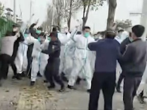 In this photo provided Nov 23, 2022, security personnel in protective clothing attack a man during protest at the factory compound operated by Foxconn Technology Group who runs the world's biggest Apple iPhone factory in Zhengzhou in central China's Henan province.