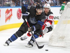 Mark Giordano of the Toronto Maple Leafs skates with the puck against a checking Jack Hughes of the New Jersey Devils at Scotiabank Arena on March 23, 2022 in Toronto, Ontario, Canada.