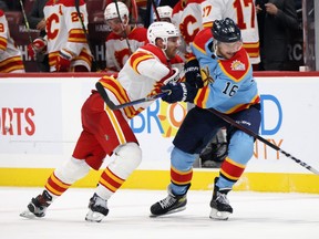 Aleksander Barkov of the Florida Panthers is checked by Jonathan Huberdeau of the Calgary Flames during the third period at FLA Live Arena on November 19, 2022 in Sunrise, Florida.