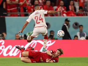 Tunisia defender Ali Abdi jumps over Denmark defender Joachim Andersen during the 2022 World Cup.